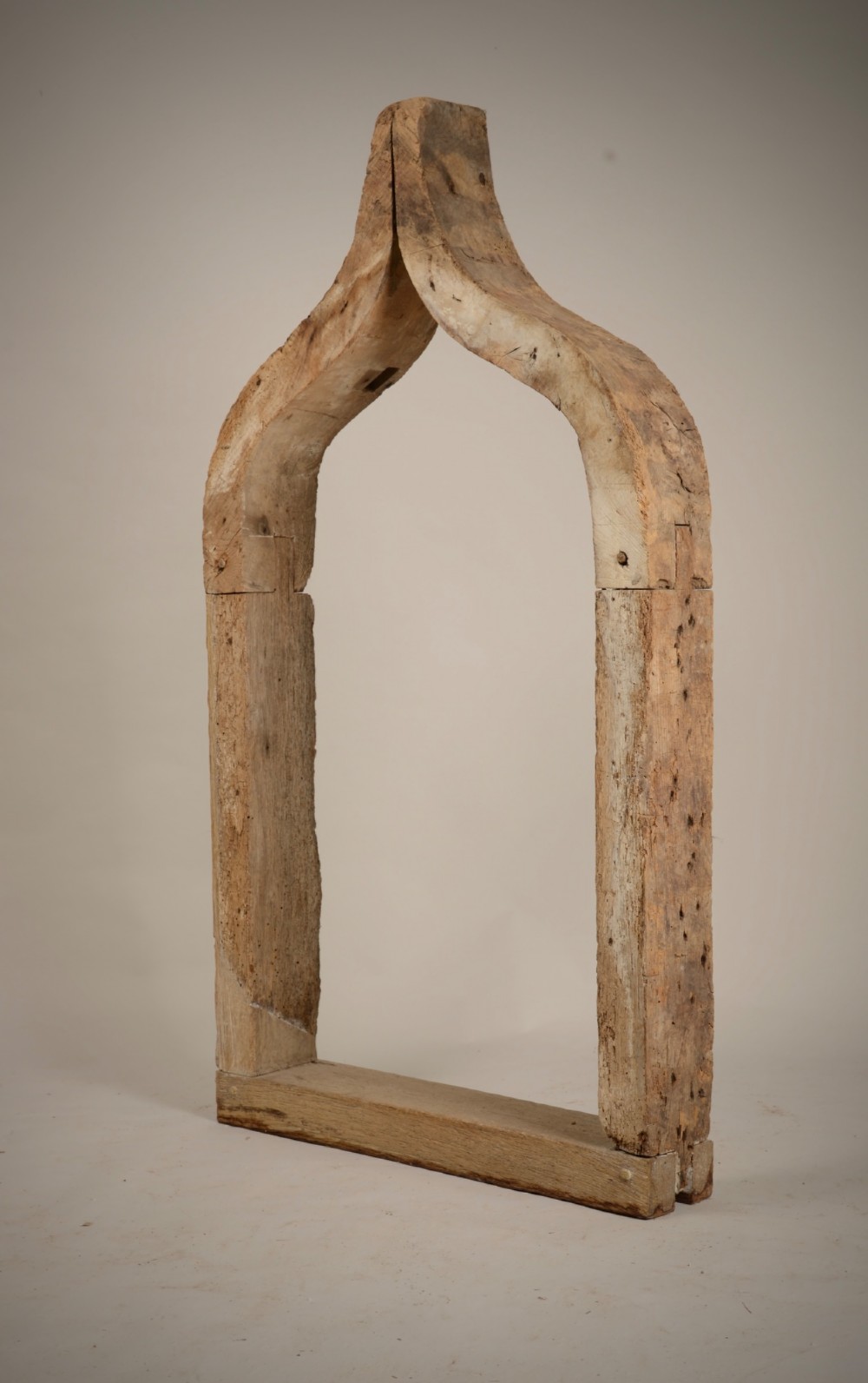 A hand-hewn oak Gothic window frame featuring a pointed arch apex and traditional pegged mortise joinery.