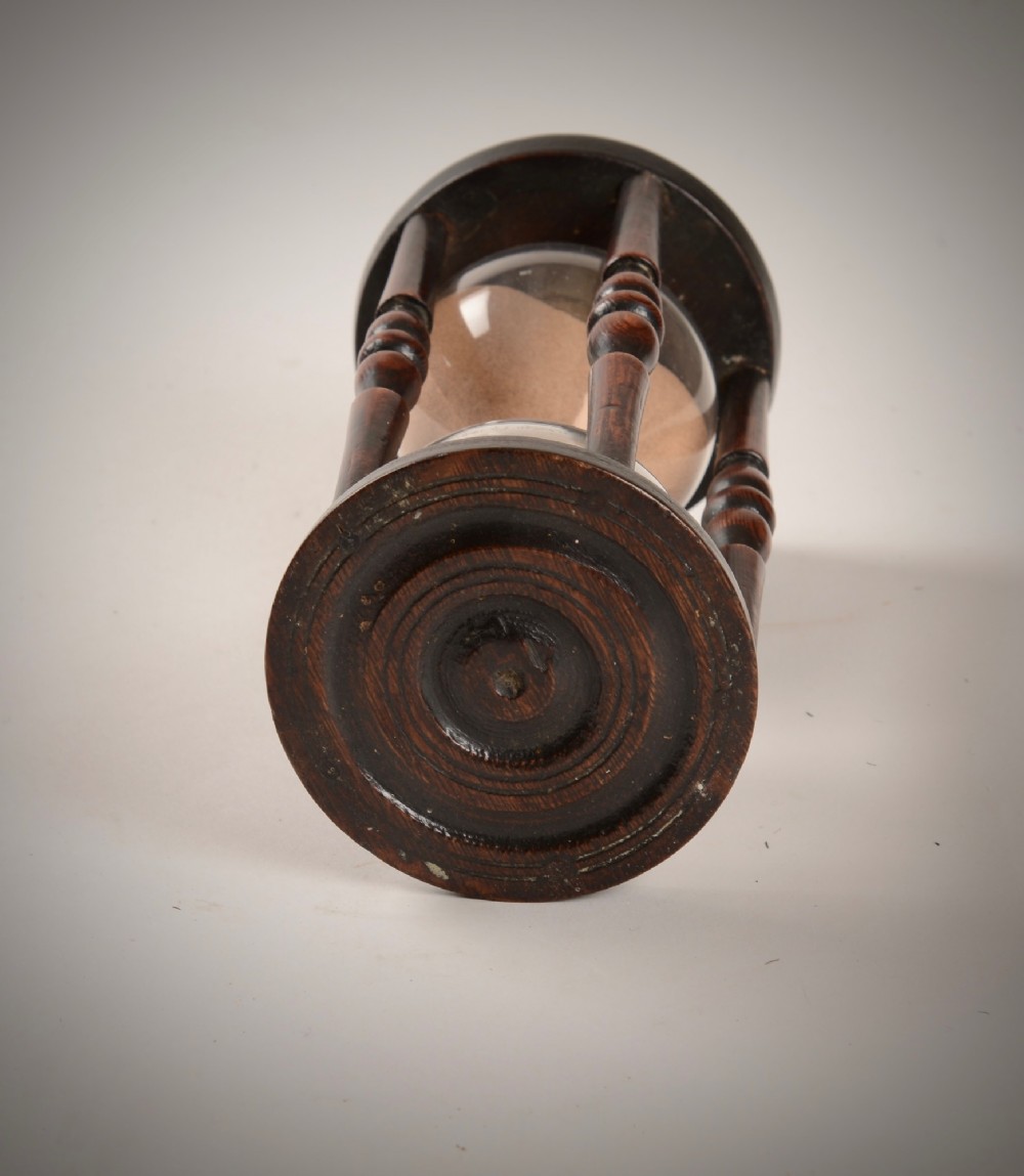 An early nineteenth-century nautical hourglass featuring a hand-blown glass vessel filled with sand, enclosed within a dark turned-wood frame. View II