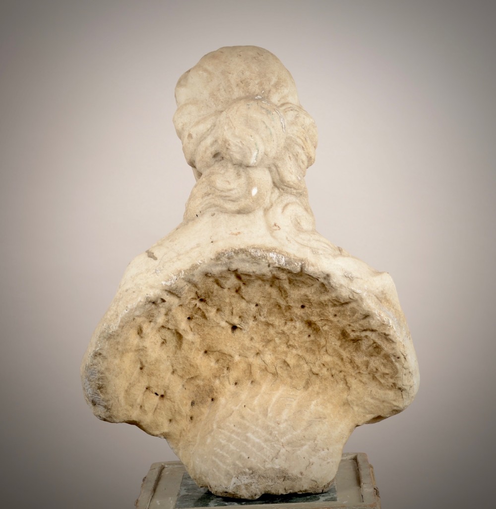 A carved off-white marble bust of a woman with classical draped clothing resting on a painted and gilded wooden pedestal. View V