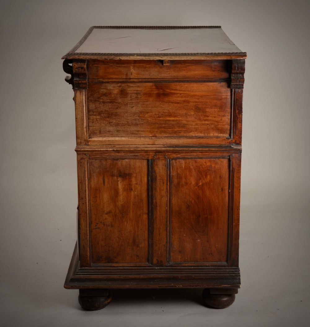 An antique warm brown walnut chest of drawers featuring geometric moulded drawer fronts, brass drop handles, and turned bun feet. View VII