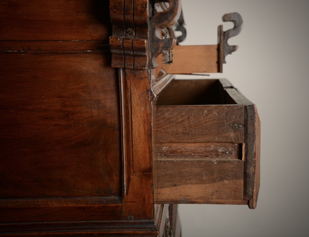 An antique warm brown walnut chest of drawers featuring geometric moulded drawer fronts, brass drop handles, and turned bun feet. View IX