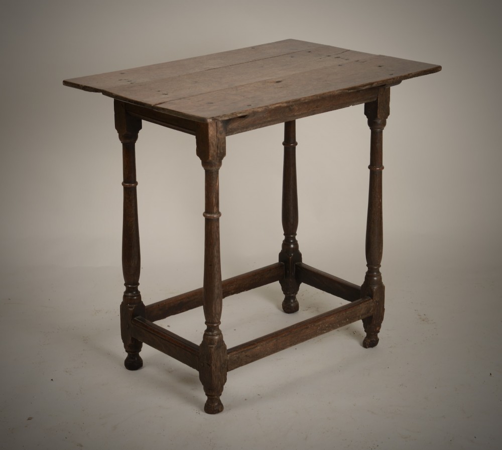 An early 18th-century dark oak tavern table featuring a rectangular plank top, turned legs, and a low box stretcher.