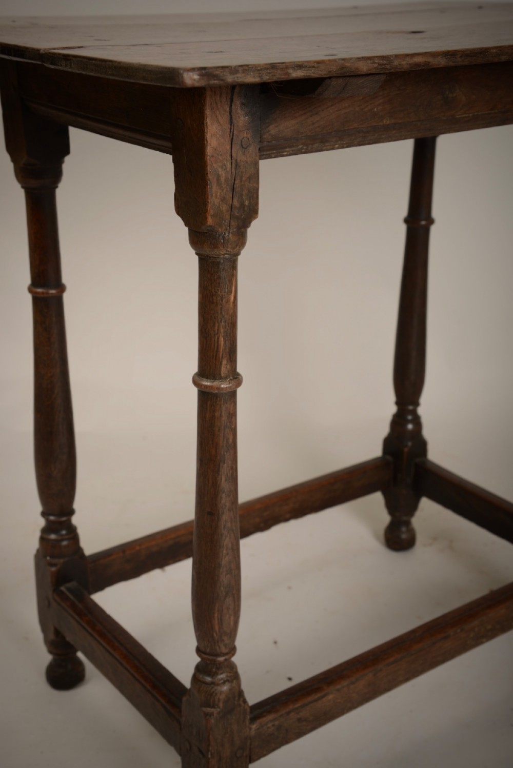 An early 18th-century dark oak tavern table featuring a rectangular plank top, turned legs, and a low box stretcher. View V