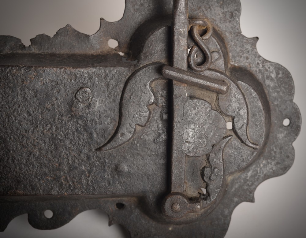A 17th-century hand-forged wrought iron rim lock featuring a scalloped decorative backplate, a surface-mounted lever latch, and aged dark metal patina. View II