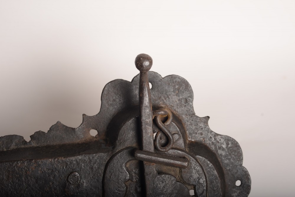 A 17th-century hand-forged wrought iron rim lock featuring a scalloped decorative backplate, a surface-mounted lever latch, and aged dark metal patina. View III