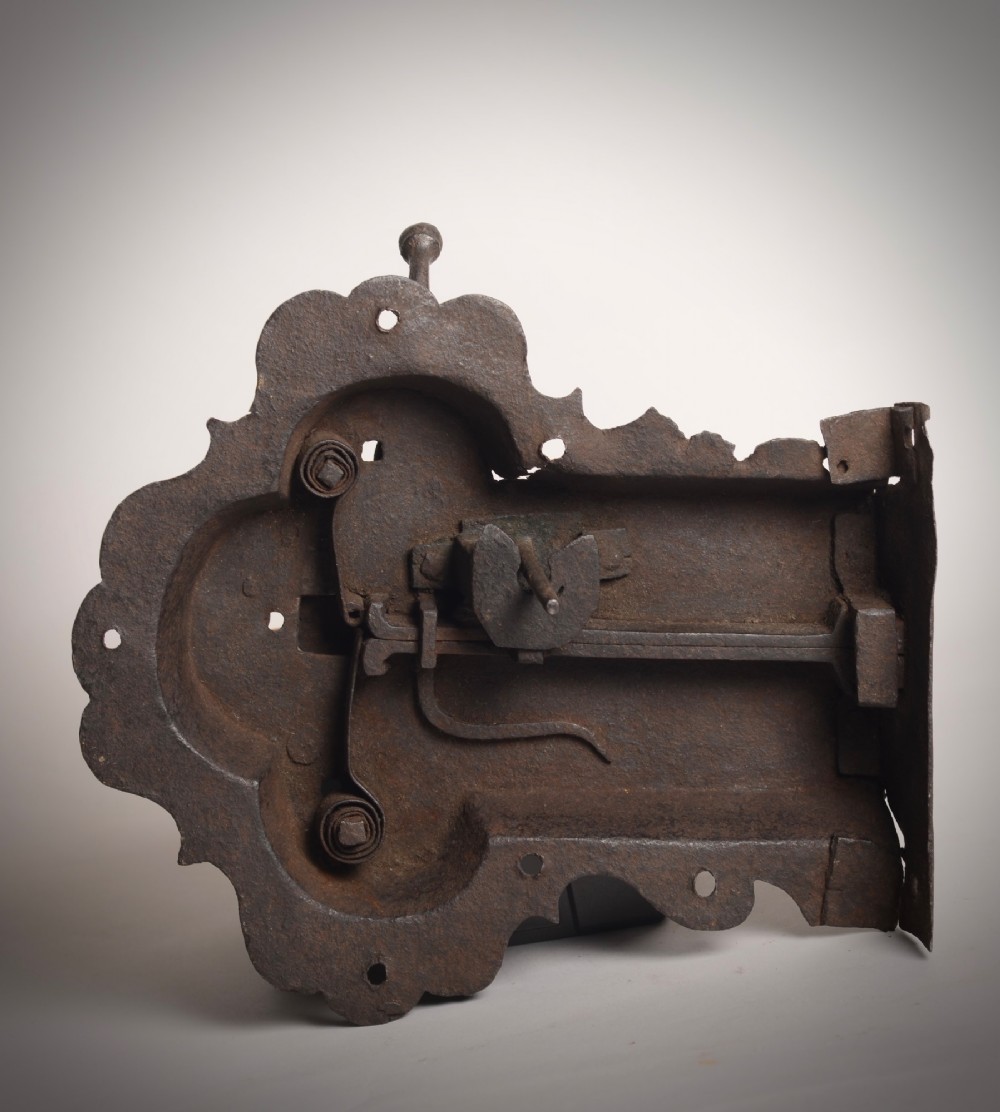 A 17th-century hand-forged wrought iron rim lock featuring a scalloped decorative backplate, a surface-mounted lever latch, and aged dark metal patina. View IV