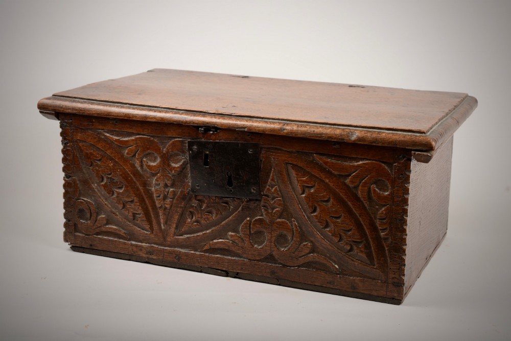 A seventeenth-century dark oak table box with relief-carved leaf and botanical scrollwork on the front panel and a central iron escutcheon plate. View II