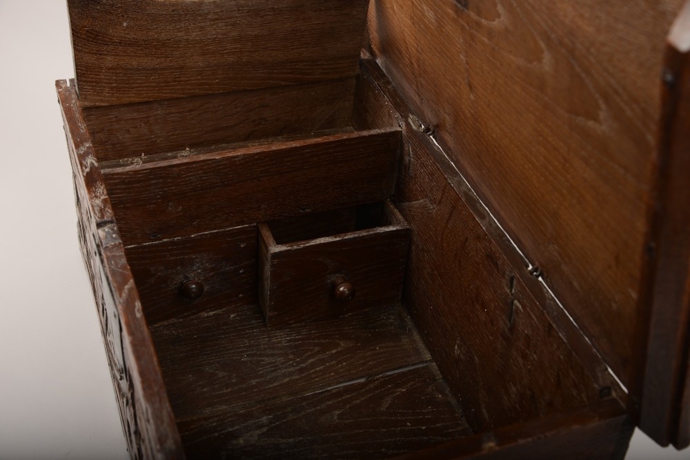 A seventeenth-century dark oak table box with relief-carved leaf and botanical scrollwork on the front panel and a central iron escutcheon plate. View VI