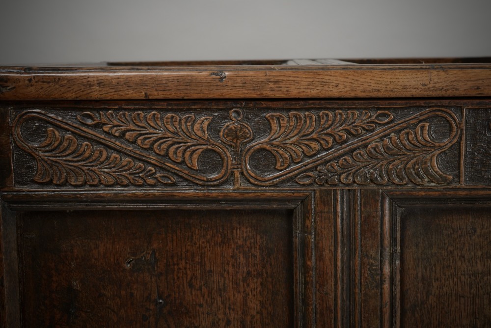 A seventeenth-century dark oak mule chest featuring four carved front panels, three lower drawers, and a carved top frieze with the initials WB and date 1679. View III