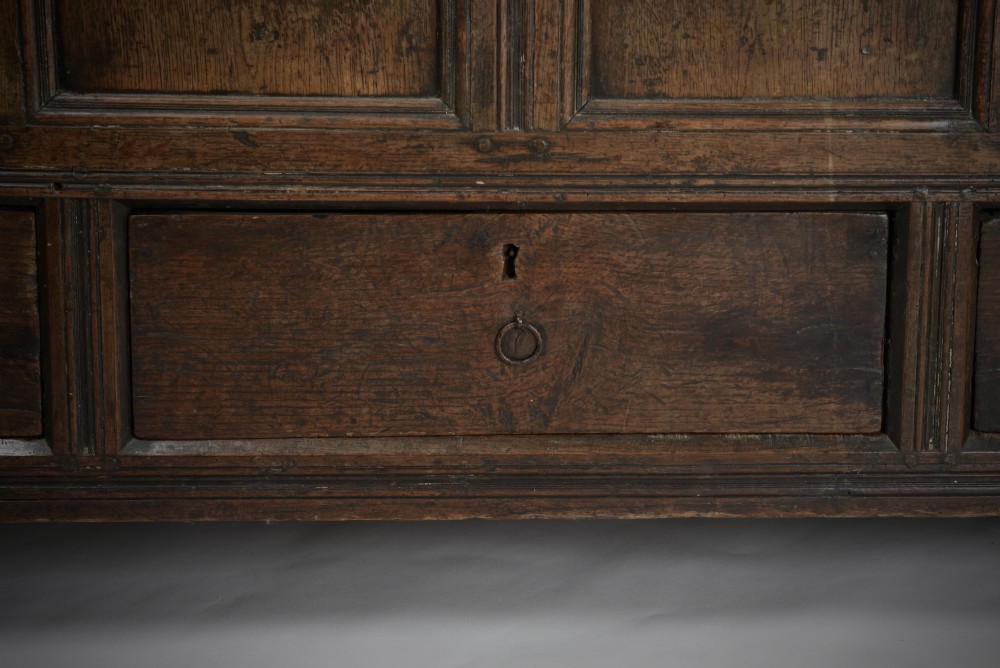 A seventeenth-century dark oak mule chest featuring four carved front panels, three lower drawers, and a carved top frieze with the initials WB and date 1679. View IV