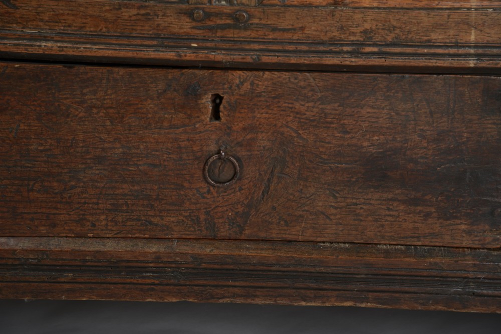 A seventeenth-century dark oak mule chest featuring four carved front panels, three lower drawers, and a carved top frieze with the initials WB and date 1679. View V