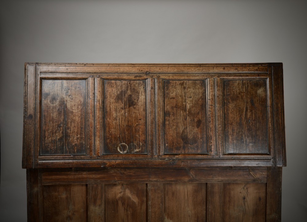 A seventeenth-century dark oak mule chest featuring four carved front panels, three lower drawers, and a carved top frieze with the initials WB and date 1679. View IX