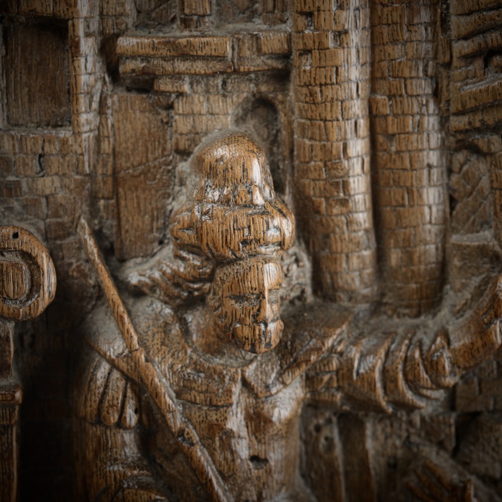 A sixteenth-century rectangular carved oak relief panel depicting a standing soldier with a staff addressing a kneeling figure within an arched architectural backdrop. View II