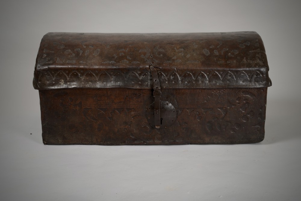 A 17th-century dark brown tooled leather coffer featuring a curved domed lid and central wrought iron lock plate. View II