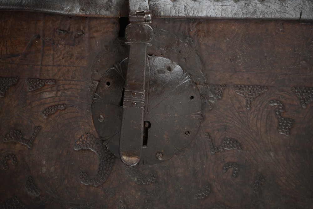 A 17th-century dark brown tooled leather coffer featuring a curved domed lid and central wrought iron lock plate. View VI