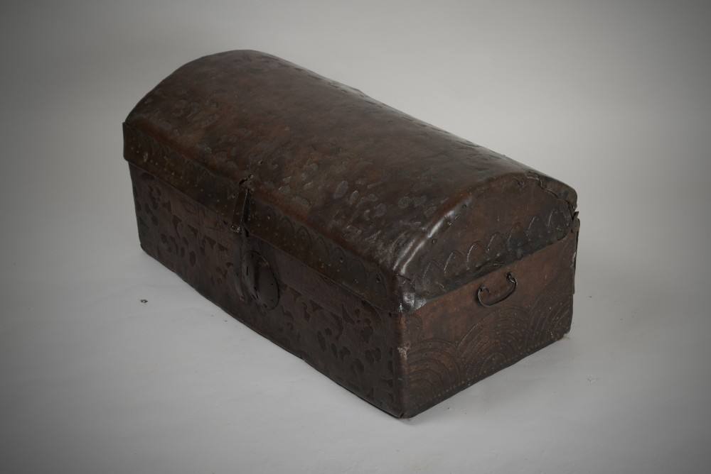 A 17th-century dark brown tooled leather coffer featuring a curved domed lid and central wrought iron lock plate. View VII