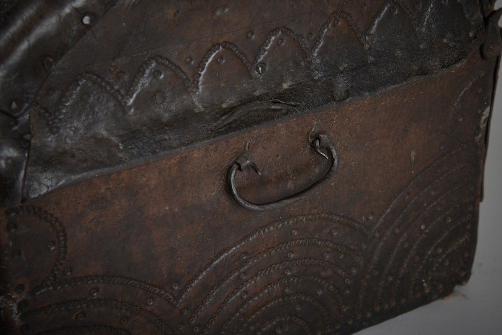 A 17th-century dark brown tooled leather coffer featuring a curved domed lid and central wrought iron lock plate. View VIII