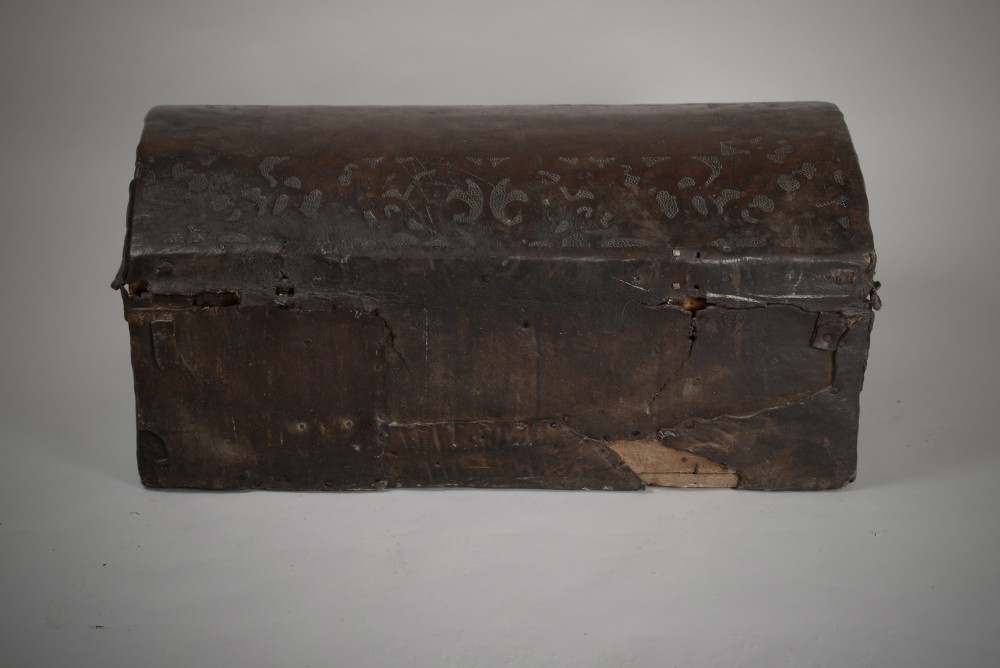 A 17th-century dark brown tooled leather coffer featuring a curved domed lid and central wrought iron lock plate. View IX