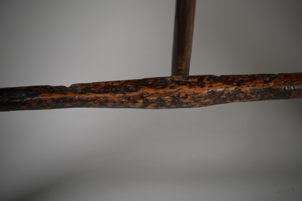 A dark brown antique wooden comb-back Windsor armchair featuring a shaped central splat, slim spindles, a contoured saddle seat, and turned legs. View VIII