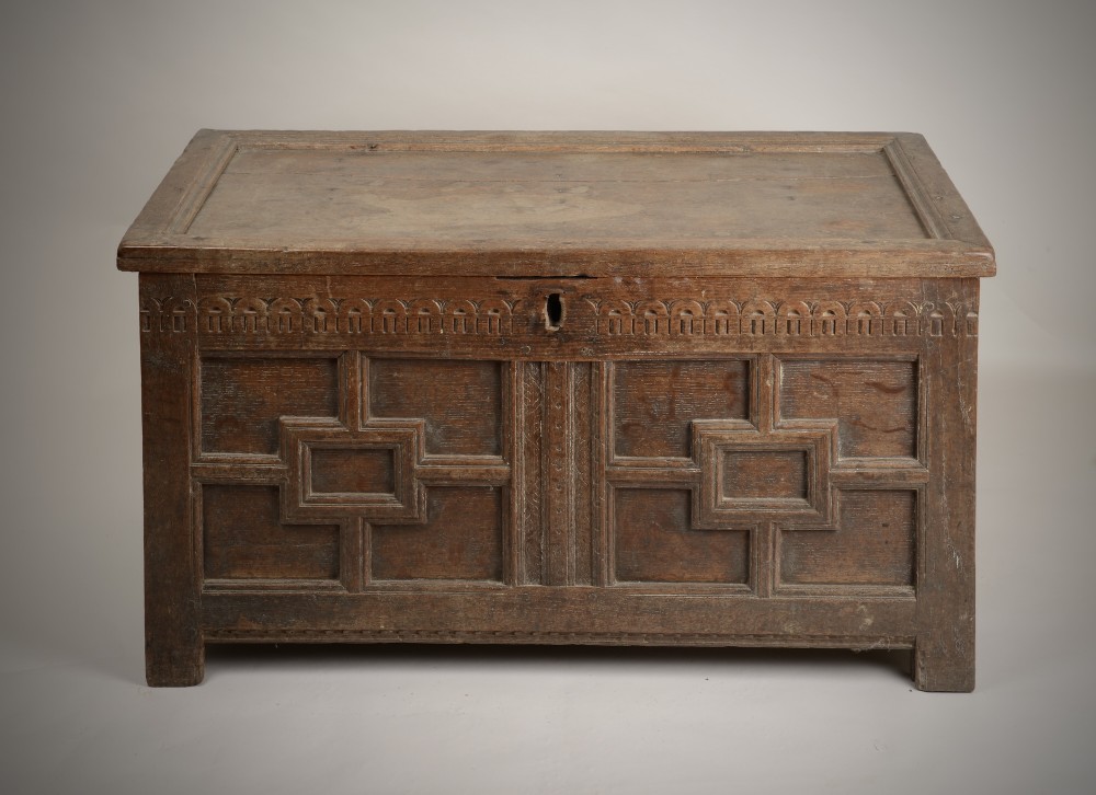 A late Elizabethan dark oak coffer featuring geometric carved front panels, an arcaded frieze, and a central keyhole. View II