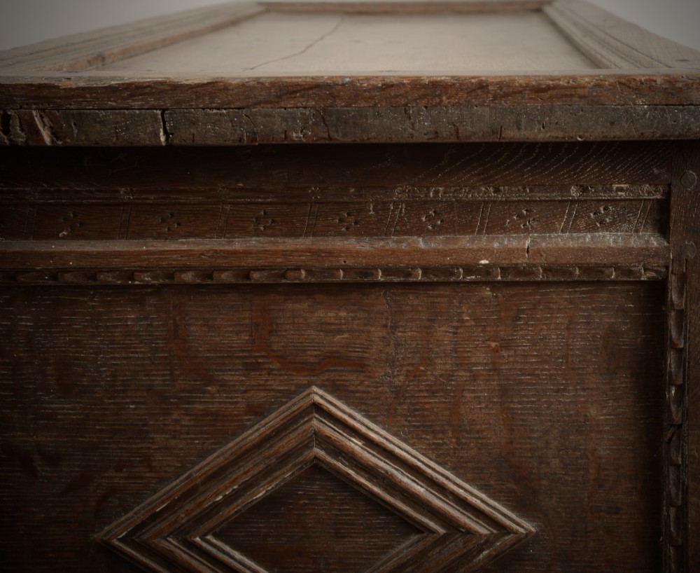 A late Elizabethan dark oak coffer featuring geometric carved front panels, an arcaded frieze, and a central keyhole. View V