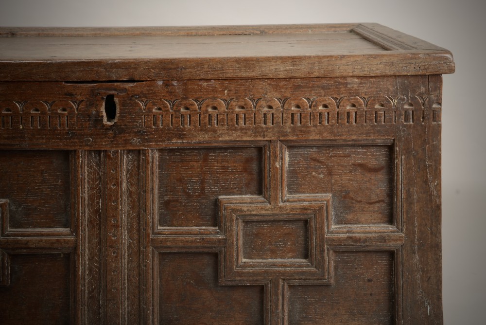 A late Elizabethan dark oak coffer featuring geometric carved front panels, an arcaded frieze, and a central keyhole. View VI
