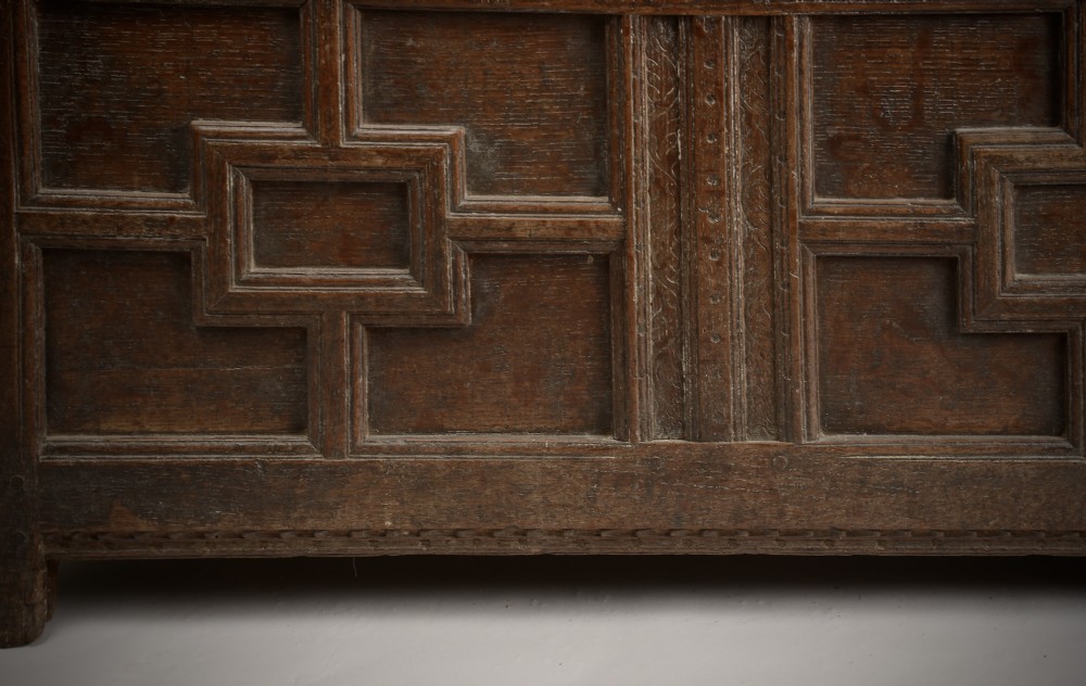 A late Elizabethan dark oak coffer featuring geometric carved front panels, an arcaded frieze, and a central keyhole. View VII