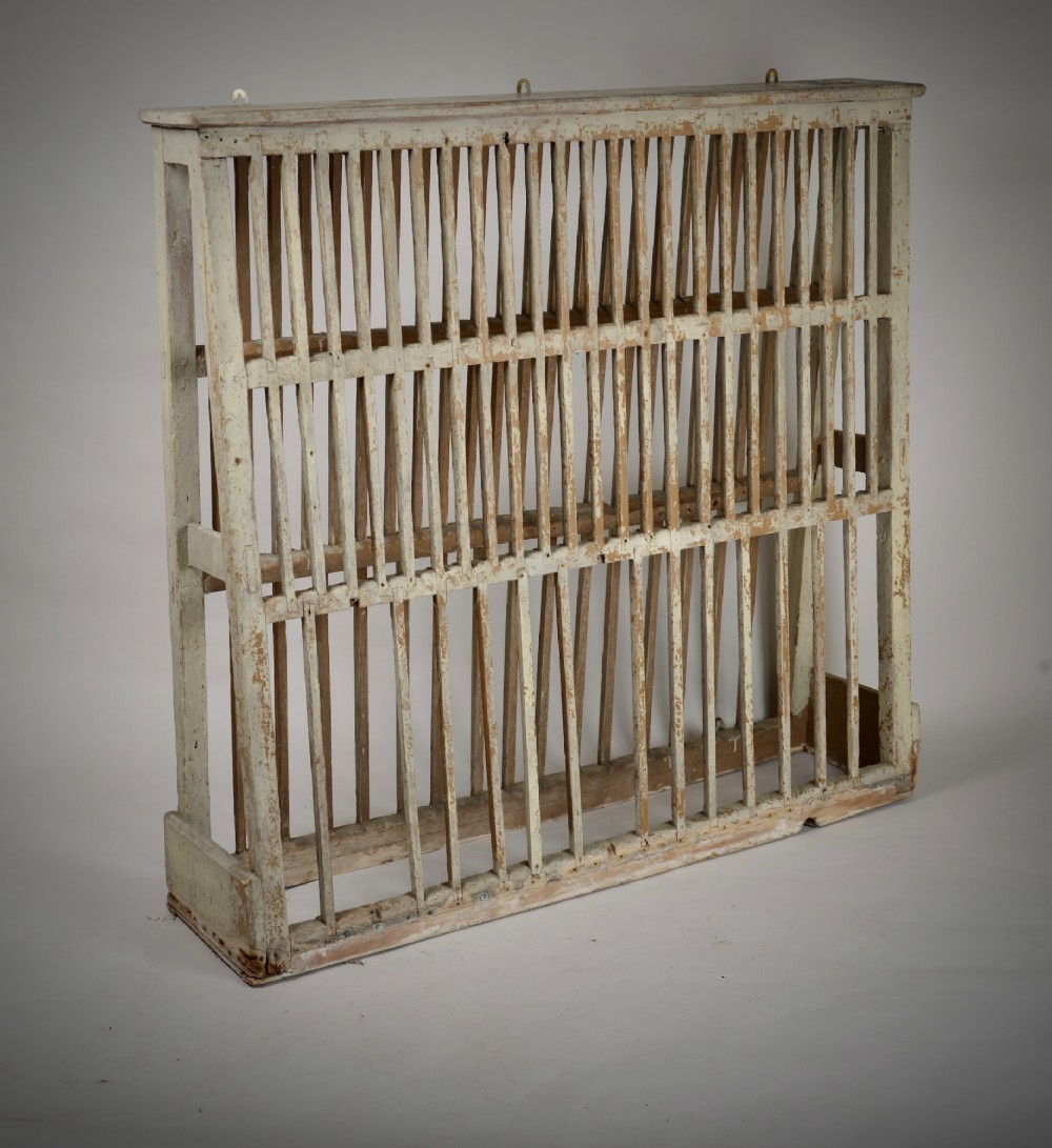 A two-tier painted wooden country house plate rack featuring a distressed off-white finish and vertical slotted spindles.