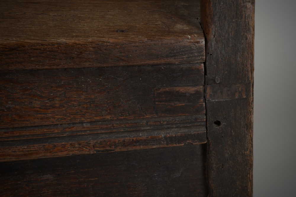 A dark oak late Elizabethan box chair featuring a high panelled back, curved armrests, and an enclosed wooden base. View III