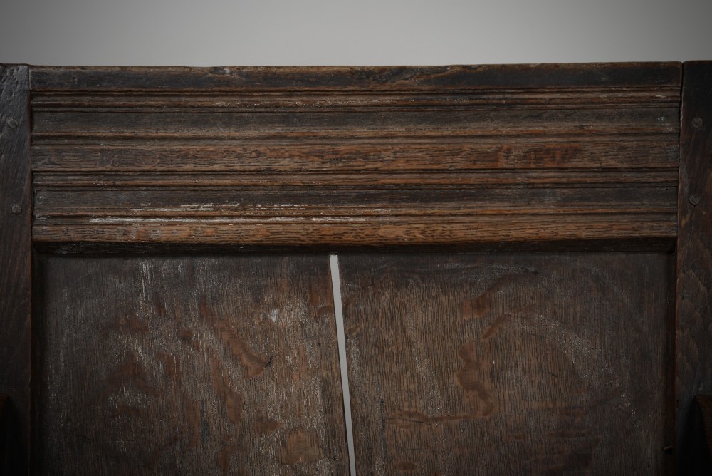 A dark oak late Elizabethan box chair featuring a high panelled back, curved armrests, and an enclosed wooden base. View IV