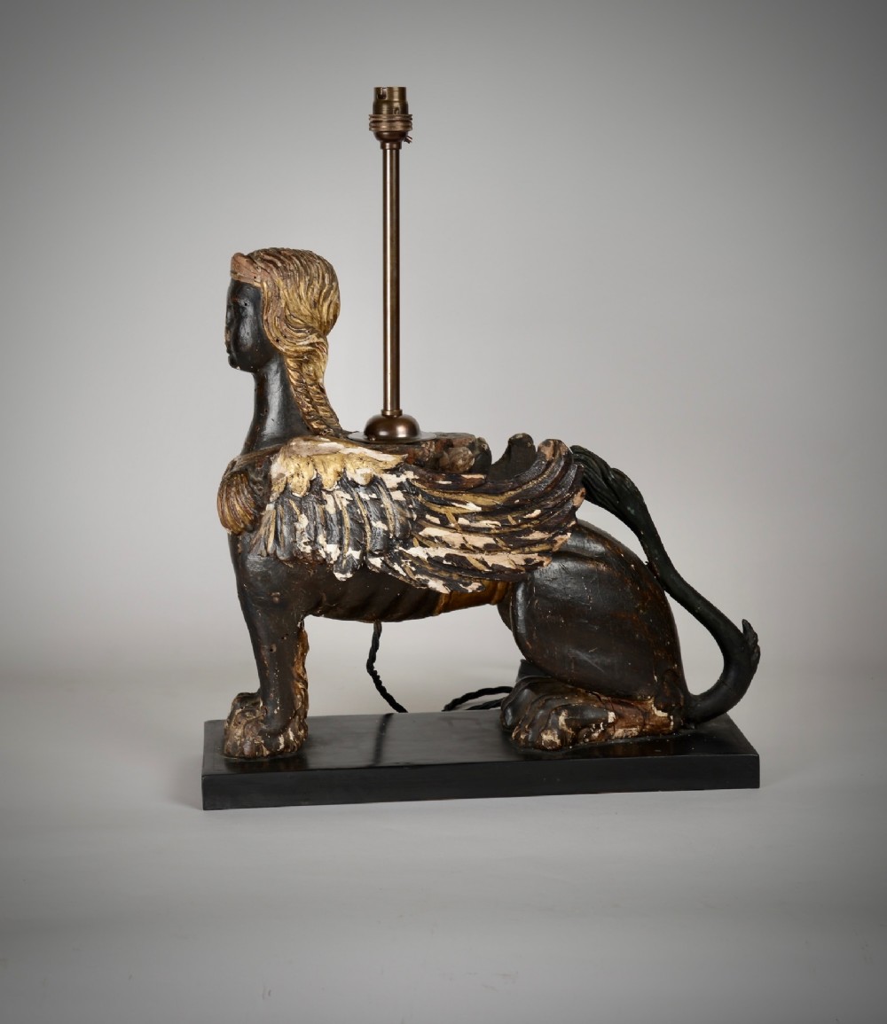 A pair of 18th-century ebonised and parcel-gilt carved wooden sphinx sculptures mounted on rectangular plinths and converted into table lamps with black shades. View III