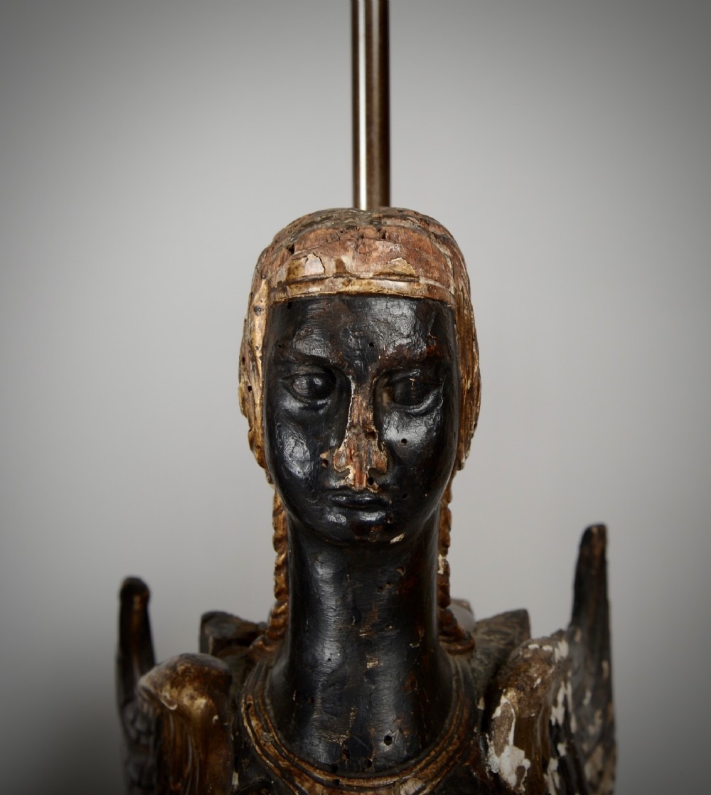A pair of 18th-century ebonised and parcel-gilt carved wooden sphinx sculptures mounted on rectangular plinths and converted into table lamps with black shades. View VII
