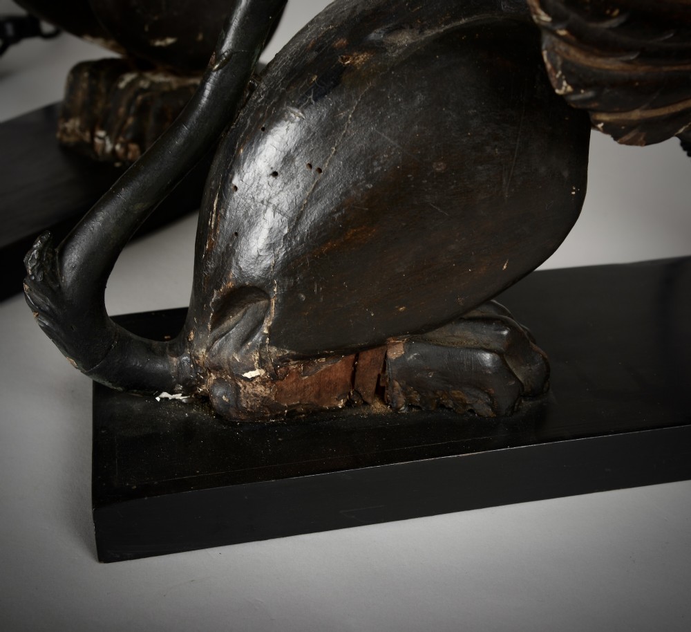 A pair of 18th-century ebonised and parcel-gilt carved wooden sphinx sculptures mounted on rectangular plinths and converted into table lamps with black shades. View X