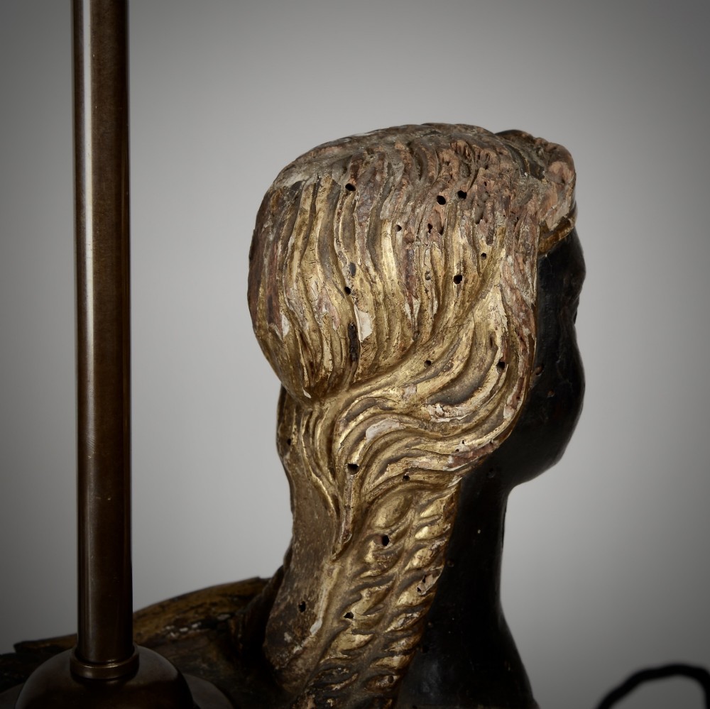 A pair of 18th-century ebonised and parcel-gilt carved wooden sphinx sculptures mounted on rectangular plinths and converted into table lamps with black shades. View XI