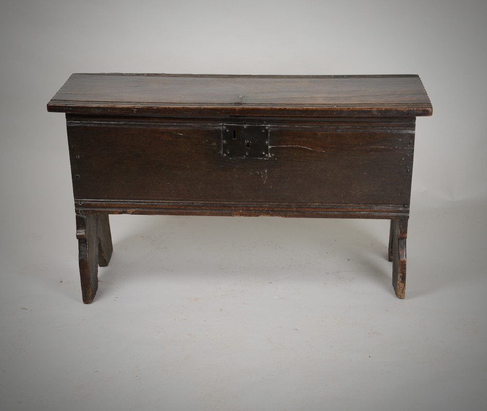A small antique dark oak six-plank coffer featuring an incised moulded top lid, hand-forged iron lockplate, and V-cut bootjack slab ends. View II