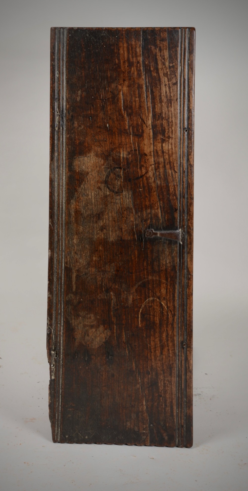 A small antique dark oak six-plank coffer featuring an incised moulded top lid, hand-forged iron lockplate, and V-cut bootjack slab ends. View V