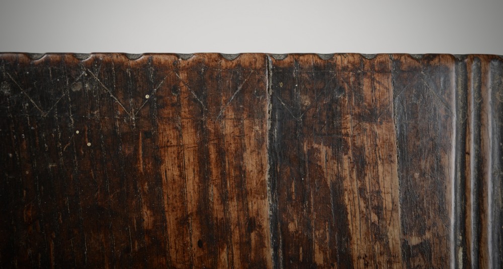 A small antique dark oak six-plank coffer featuring an incised moulded top lid, hand-forged iron lockplate, and V-cut bootjack slab ends. View VI