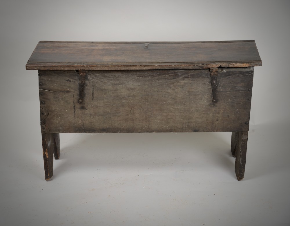 A small antique dark oak six-plank coffer featuring an incised moulded top lid, hand-forged iron lockplate, and V-cut bootjack slab ends. View VII