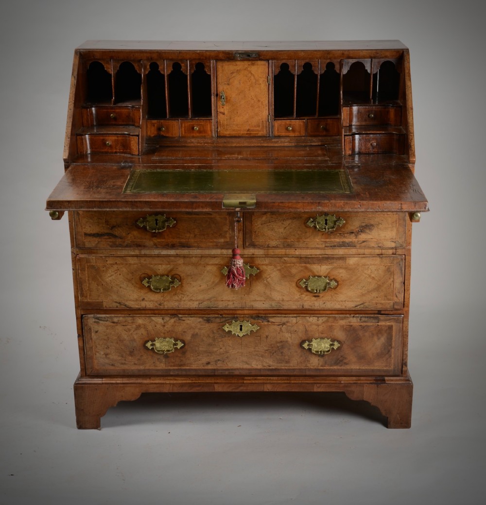 An 18th-century George II burr walnut bureau featuring a sloped fall-front flap above four graduated drawers with brass handles and bracket feet. View II
