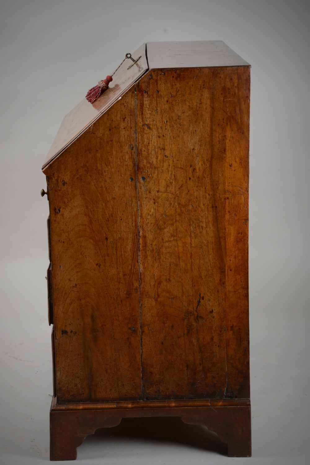 An 18th-century George II burr walnut bureau featuring a sloped fall-front flap above four graduated drawers with brass handles and bracket feet. View XII