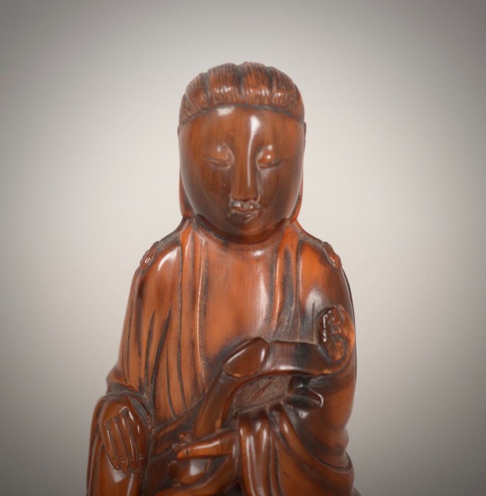 A hand-carved honey-brown horn figure depicting the Chinese deity Guanyin in flowing draped robes. View V