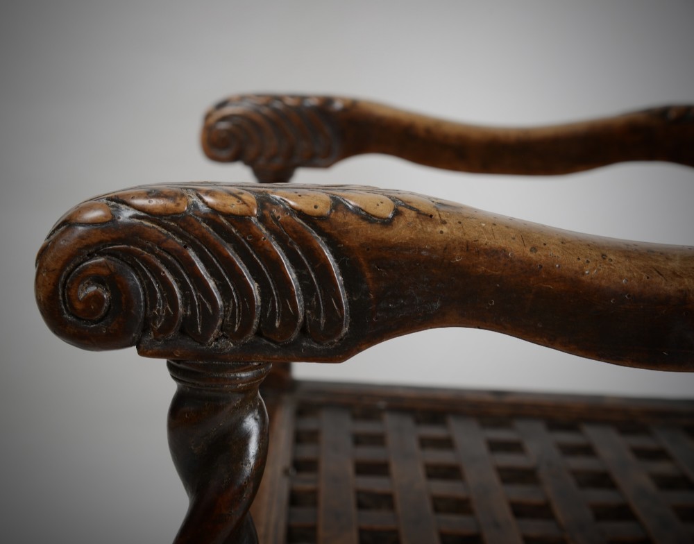 A dark walnut Charles II style open armchair featuring intricate barley twist uprights, a carved floral cresting rail, a slatted timber lattice back, and turned stretchers. View V