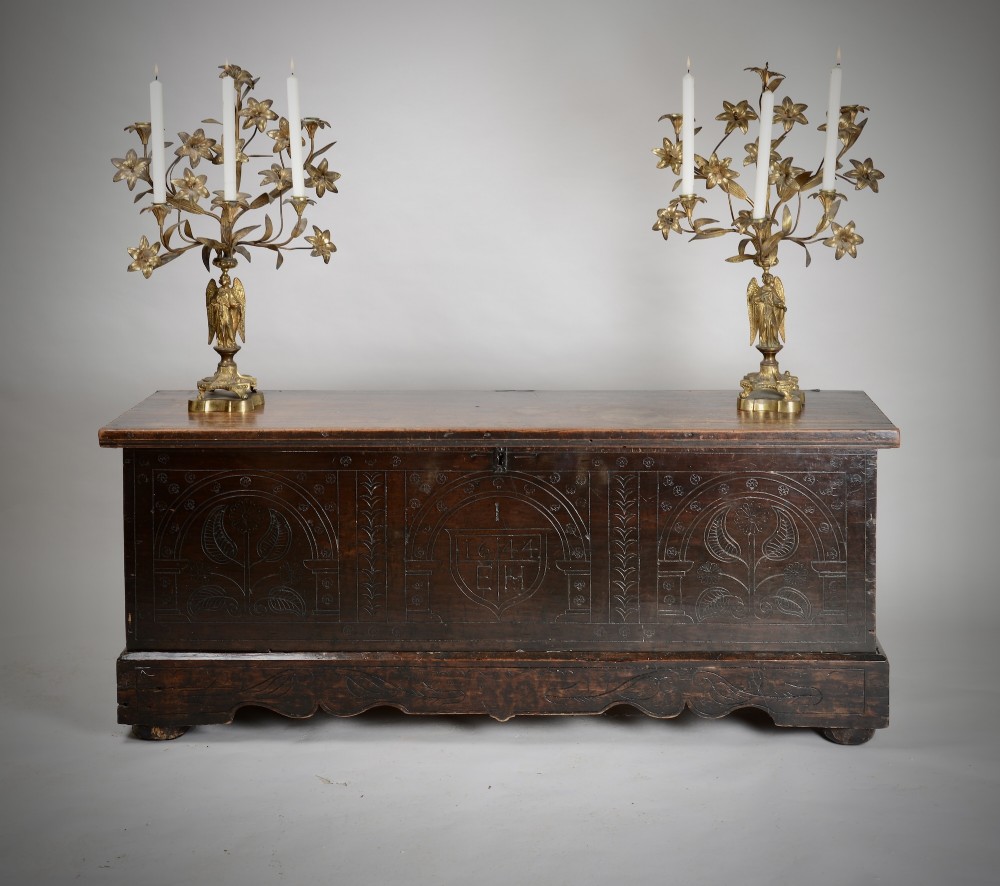 A dark brown 17th-century carved oak coffer featuring three carved arch panels, a central shield panel inscribed with the date 1644, and a shaped lower apron. View V