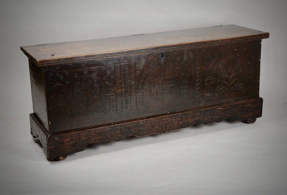 A dark brown 17th-century carved oak coffer featuring three carved arch panels, a central shield panel inscribed with the date 1644, and a shaped lower apron. View VI