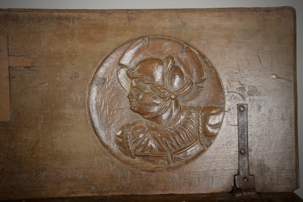 A Renaissance style carved wooden bench featuring two profile portrait roundels flanking a central cross on the backrest and wrought iron support stretchers beneath. View IV