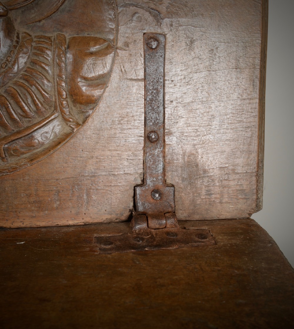 A Renaissance style carved wooden bench featuring two profile portrait roundels flanking a central cross on the backrest and wrought iron support stretchers beneath. View VI