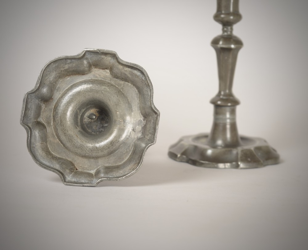 A pair of 18th-century pewter candlesticks featuring baluster stems and shaped scalloped bases. View II