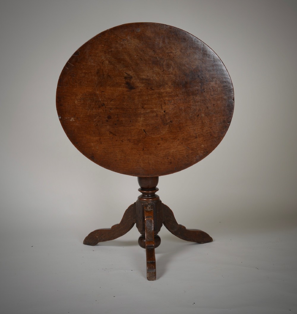 An antique dark brown oak tripod table featuring a circular top, a birdcage support mechanism, a turned central column, and three splayed feet. View II