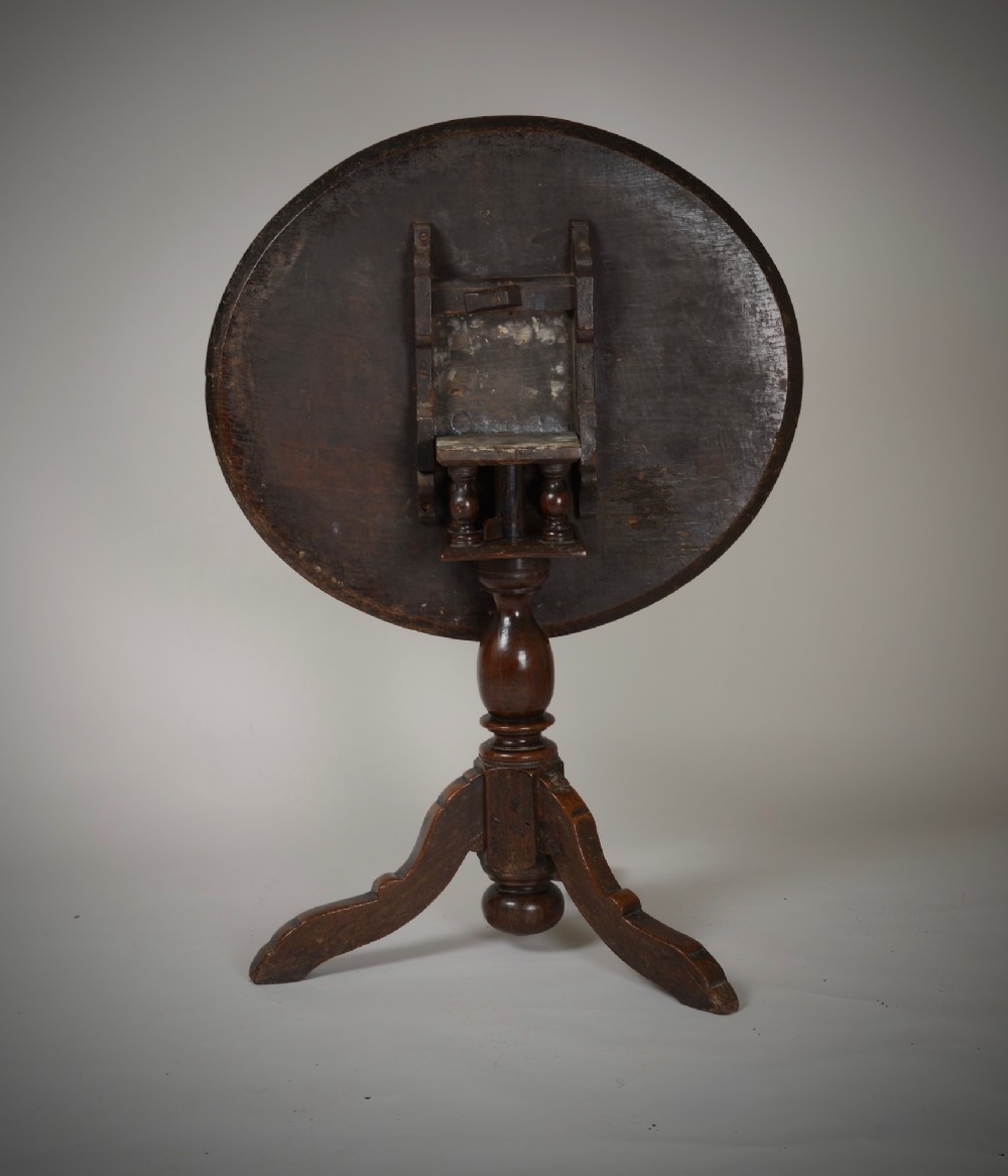 An antique dark brown oak tripod table featuring a circular top, a birdcage support mechanism, a turned central column, and three splayed feet. View III