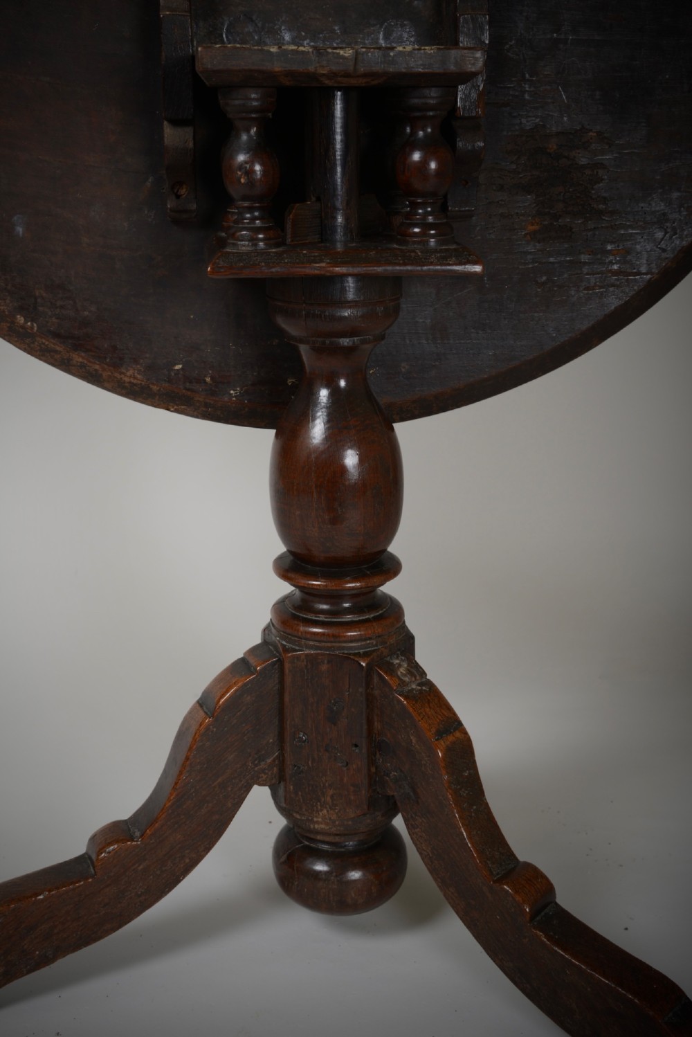 An antique dark brown oak tripod table featuring a circular top, a birdcage support mechanism, a turned central column, and three splayed feet. View VII